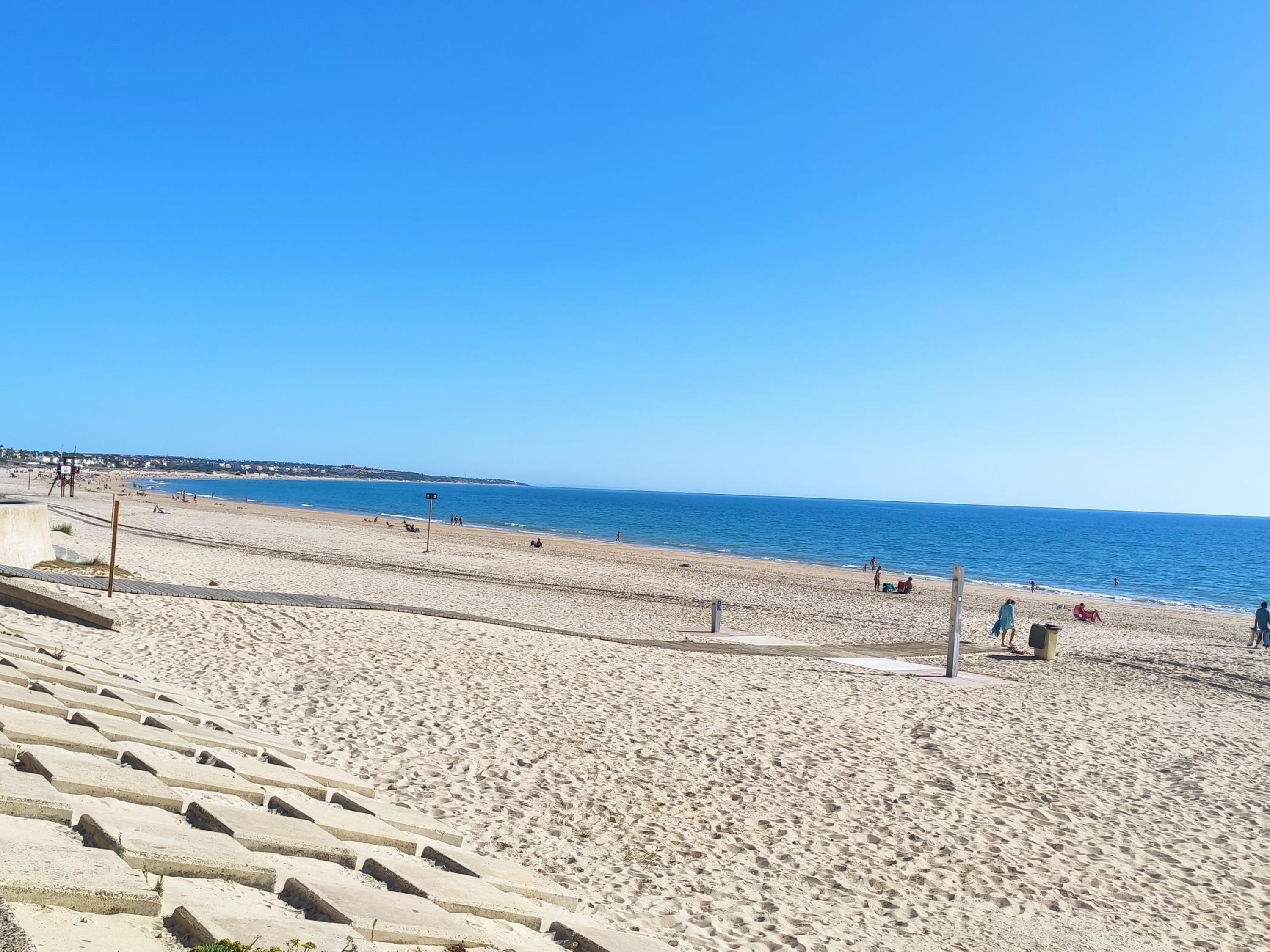 Ein weiter Sandstrand bei blauem Himmel.