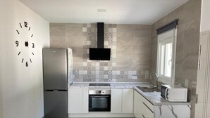 A modern kitchen with a stainless steel refrigerator, oven, and microwave, a tiled backsplash, and a window with a view. - Villa El Lagar 14238 (Chiclana de la Frontera)