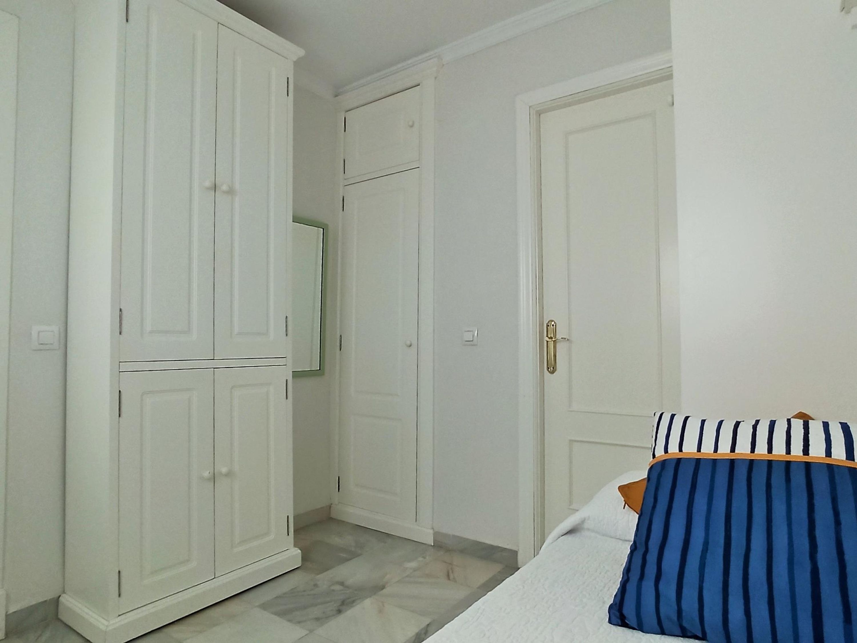 A bedroom with a bed, a wardrobe, and a door.