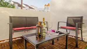 A patio with two metal chairs, a table, a bottle, and a glass. - Apartaclub 14116 in Chiclana (Chiclana de la Frontera)
