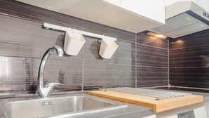 A modern kitchen with a stainless steel sink, a wooden cutting board, and a built-in oven. - Apartaclub 14116 in Chiclana (Chiclana de la Frontera)