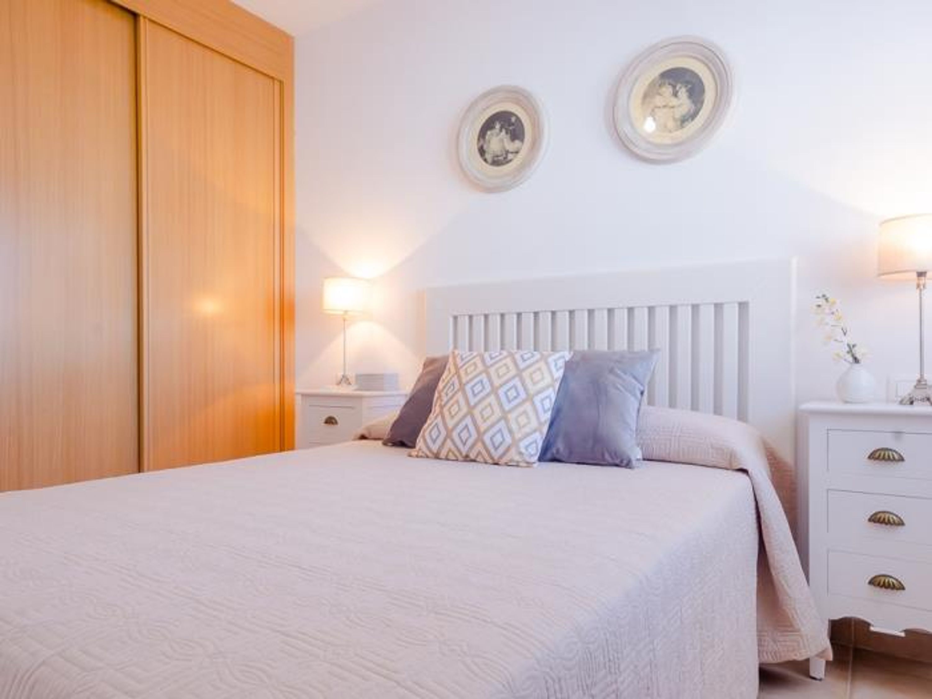 Un dormitorio con cama, mesitas de noche y un armario.