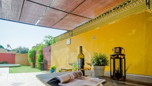 An outdoor patio with a wooden table, a wine bottle, wine glasses, and a lantern. - Villa Las Palomas 14988 (Chiclana de la Frontera)