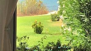 A view from inside a room looking out to a grassy area with a body of water and a beach in the distance. - Villa Laura 24952 in Conil de la Frontera (Conil de la Frontera)