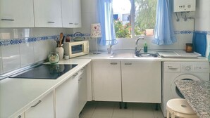 A kitchen with white cabinets, a microwave, a sink, and a washing machine. - La Almadraba A7 147 in Chiclana (Chiclana de la Frontera)