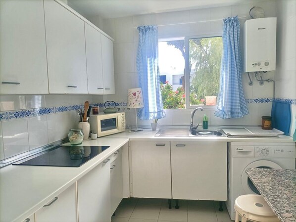 A kitchen with white cabinets, a microwave, a sink, and a washing machine. - La Almadraba A7 147 in Chiclana (Chiclana de la Frontera)