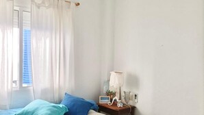 A bedroom with a bed, a bedside table with a lamp, and a window with curtains. - La Almadraba A7 147 in Chiclana (Chiclana de la Frontera)