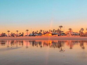 A beachfront hotel with a pool, palm trees, and a sunset. - La Almadraba A7 147 in Chiclana (Chiclana de la Frontera)
