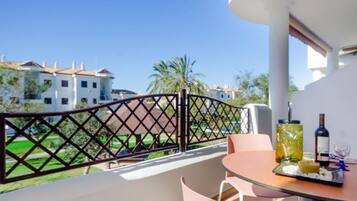 A balcony with a table set for dining, a glass of wine, and a bottle of wine.