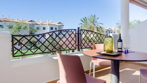 A balcony with a table, chairs, and a bottle of wine.
