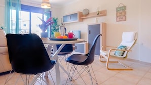 A modern living room with a dining area, a sofa, a coffee table with fruits, and a chair. - Coto de Sancti Petri 9 (Chiclana de la Frontera)