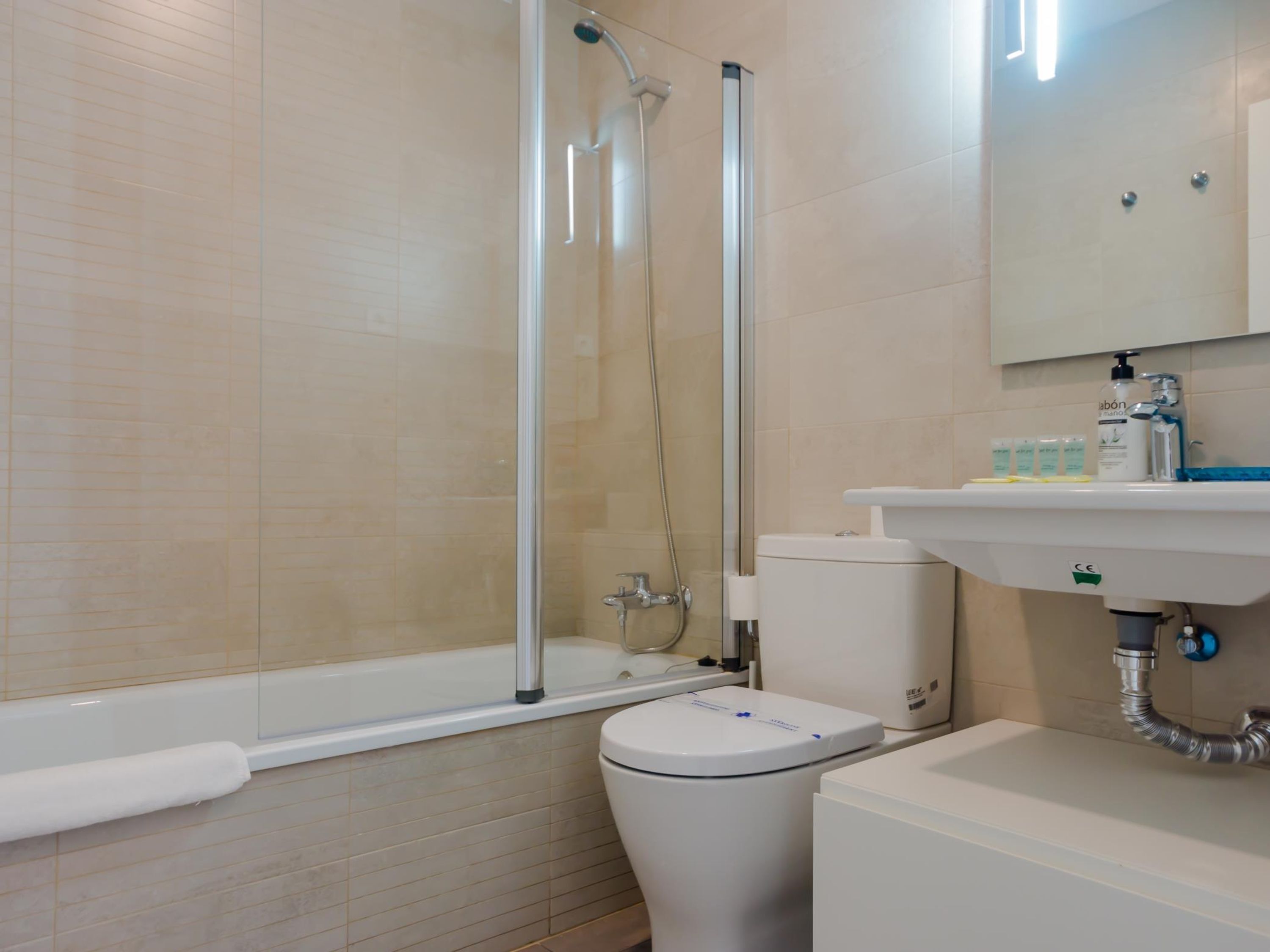 A modern bathroom with a glass-enclosed shower, a toilet, and a sink with toiletries.
