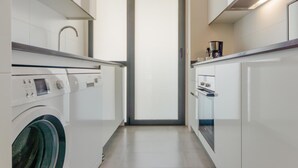A modern kitchen with a built-in washing machine, a coffee maker, and a window with frosted glass. - Bah a Blanca III 18925 (El Puerto de Santa Maria)