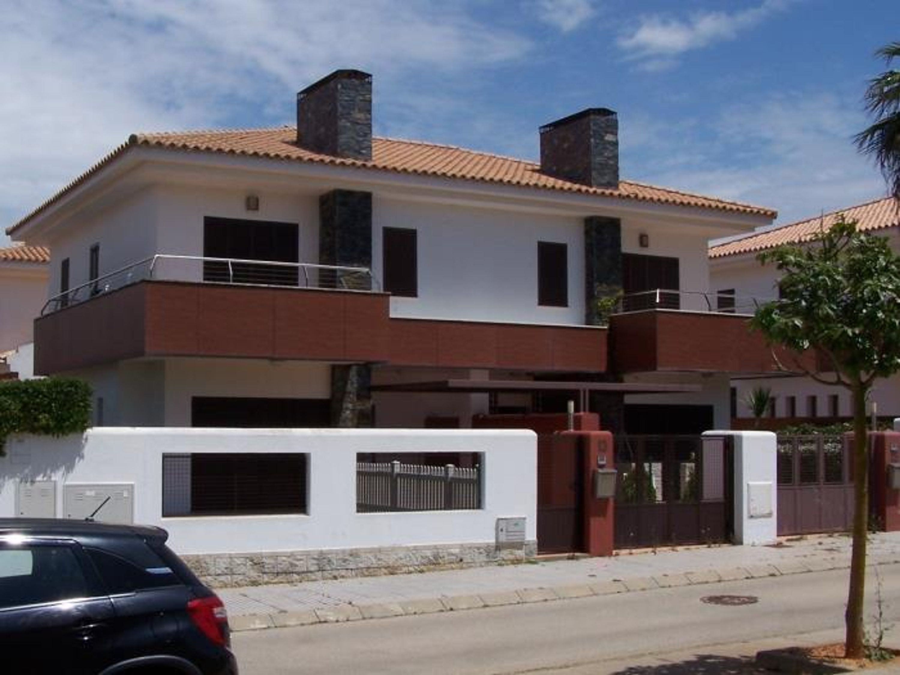 Ein zweistöckiges Haus mit Balkon, Garage und geschlossenem Eingangstor.