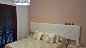 A bedroom with a bed, nightstands, and a window with blinds. - Dunas 13 in Chiclana (Chiclana de la Frontera)