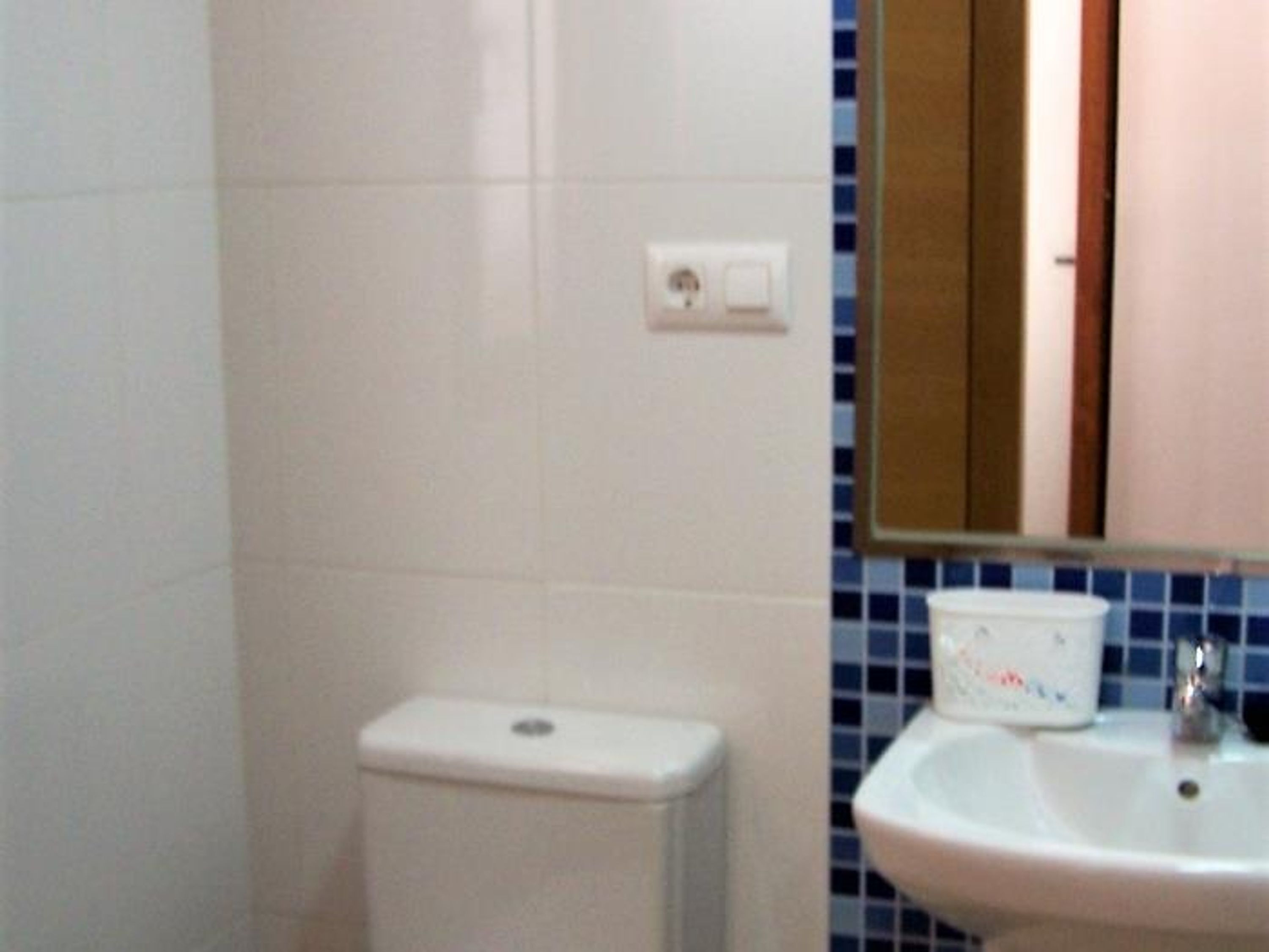 A bathroom with a white toilet, a sink, and a mirror.