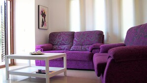 A living room with a purple sofa, a white coffee table, and a painting on the wall. - Dunas 13 in Chiclana (Chiclana de la Frontera)