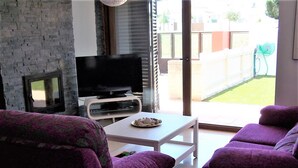 A living room with purple sofas, a flat-screen TV, and a small table with a plate. - Dunas 13 in Chiclana (Chiclana de la Frontera)