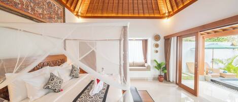 A bedroom with a canopy bed, a large mural on the wall, and a view of the outdoor area.