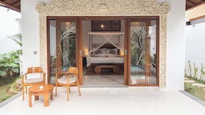 A bedroom with a canopy bed, a wooden chair, a small table, and a decorative ceiling. - Daruma Villa Sebatu (Sebatu)