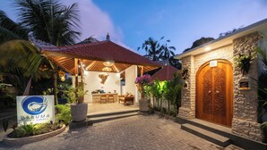 A hotel entrance with a stone facade, a wooden double door, and a covered outdoor seating area with a tiled roof. - Daruma Villa Sebatu (Sebatu)