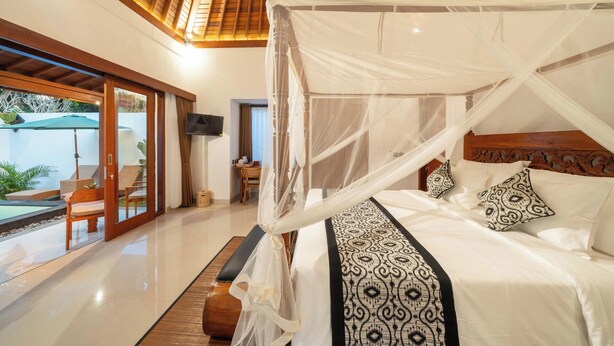 A spacious bedroom with a large bed, a wooden ceiling, and a view of an outdoor area with a pool and chairs. - Daruma Villa Sebatu (Sebatu)