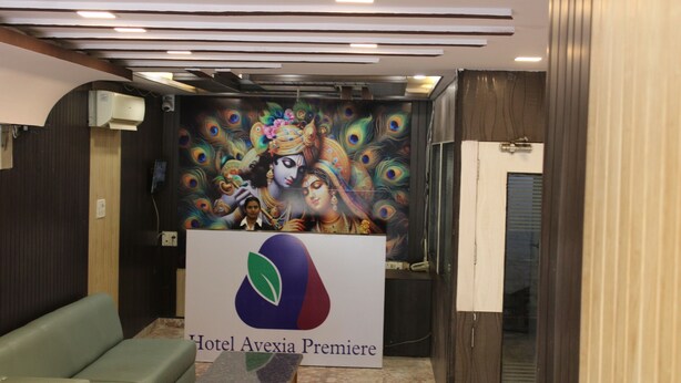 A hotel lobby with a peacock mural, a reception desk, and a green sofa. - Avexia Premiere (Chittorgarh)