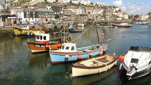 A harbor with various boats docked, surrounded by residential buildings. - Bumblebee Cottage (Bodmin)