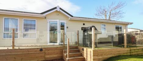 A single-story mobile home with a front porch, a sliding glass door, and a small set of wooden steps leading to the entrance.