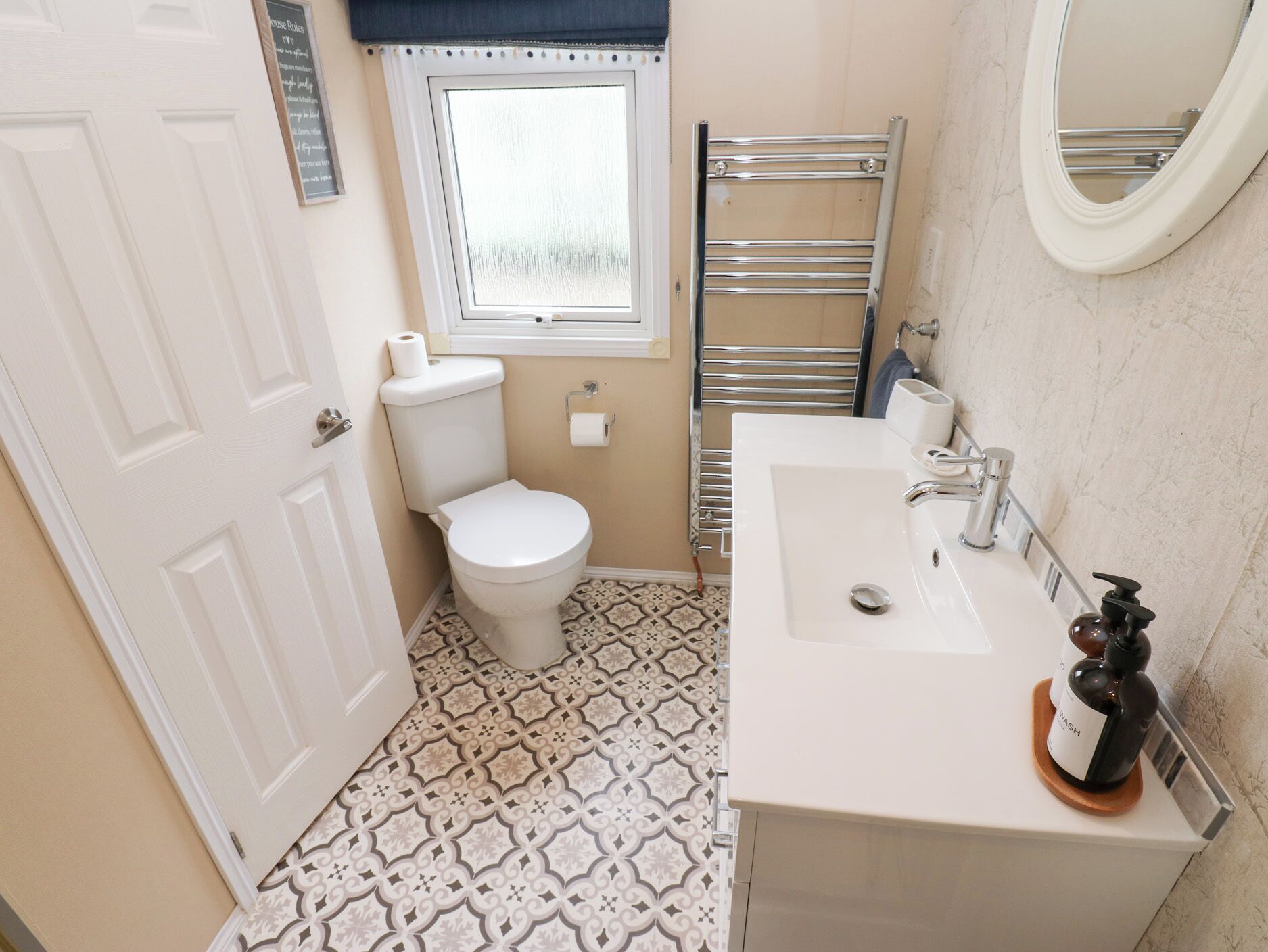 A bathroom with a toilet, a sink, a towel rack, and a window.
