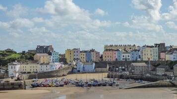 Une ville côtière aux bâtiments aux couleurs vives, avec une plage de sable et des bateaux.
