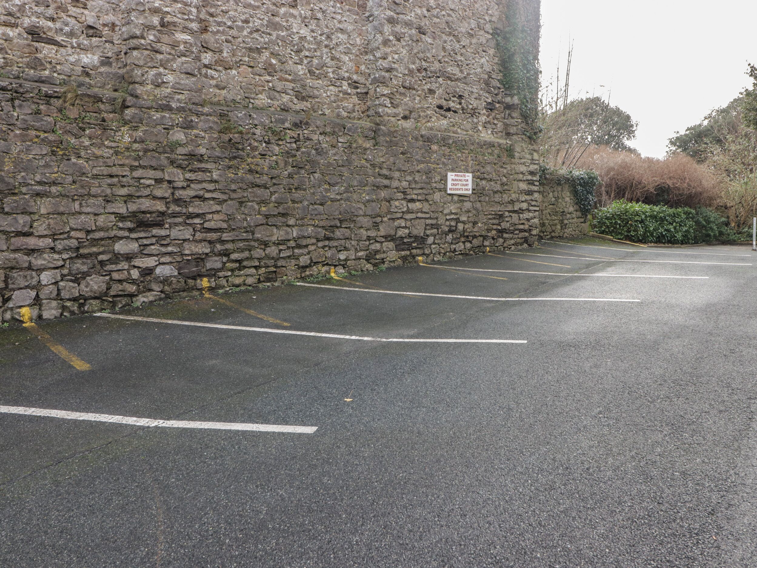 Ein Parkplatz mit Steinmauern und einem Schild, das weist darauf hin, dass die Parkplätze nur für Bewohner von Croft Court reserviert sind.