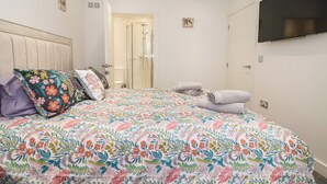 Un dormitorio con cama, ducha y televisor montado en la pared.