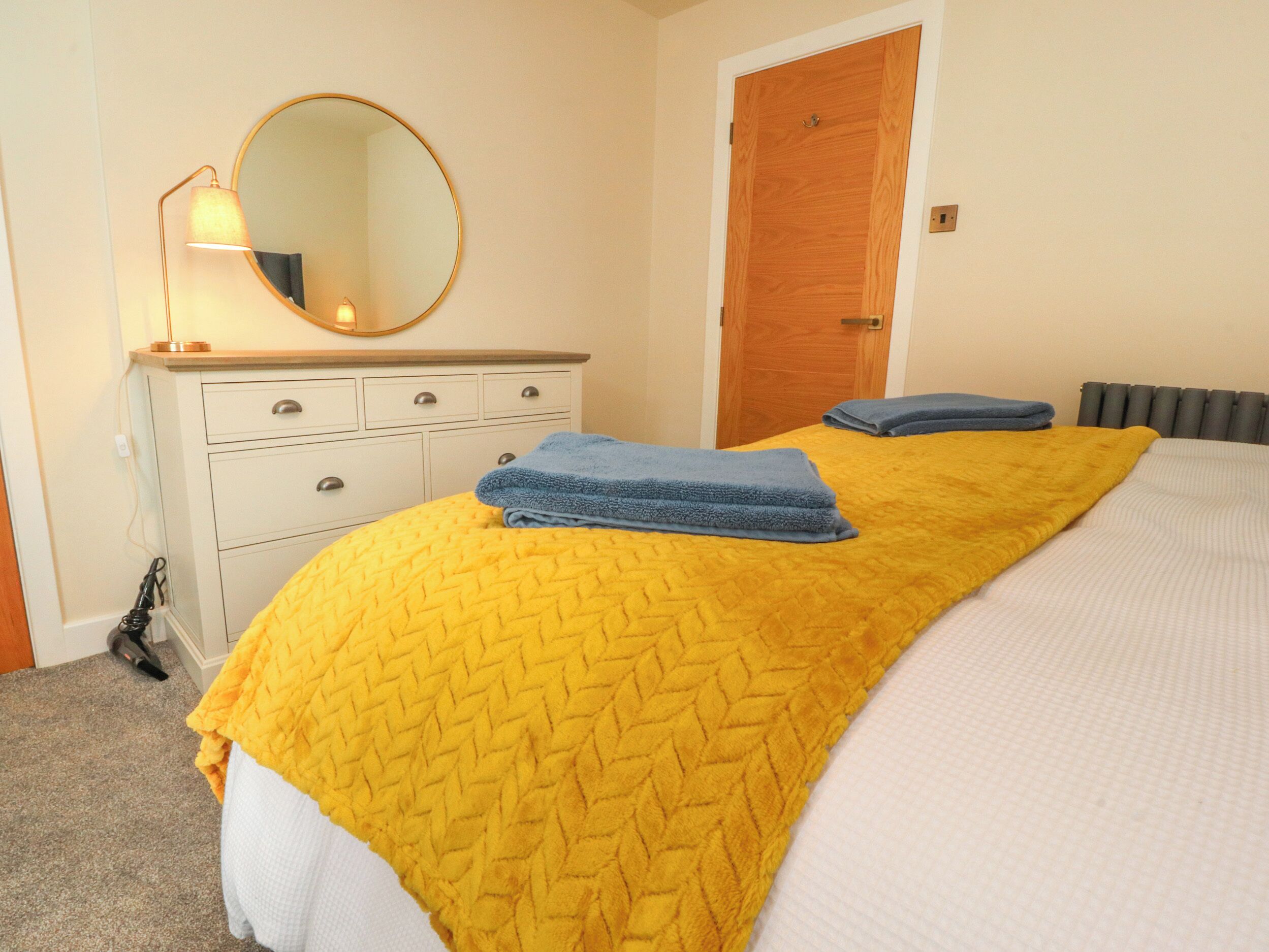 A bedroom with a bed, a dresser, a mirror, and a door.