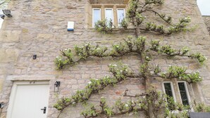 A stone building with a traditional architectural style, featuring a large window and a door. - Pear Tree Cottage at Hey Farm (Barnoldswick)