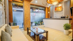 A modern lobby with a sofa, a glass coffee table, a reception desk, and a chandelier.