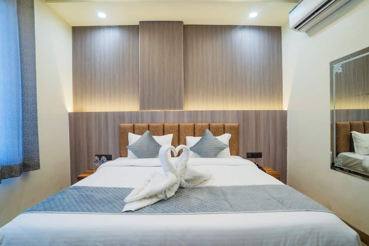 Habitación de hotel con una cama grande, cabecera con listones verticales y aire acondicionado de pared.
