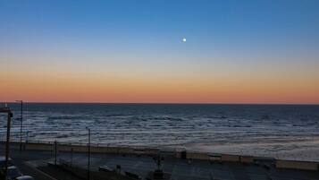 A coastal road with a view of the sea and a moon in the sky.