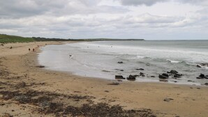 A beach with a sandy shore, scattered rocks, and a cloudy sky. - Doonalton House (Doonaltan)