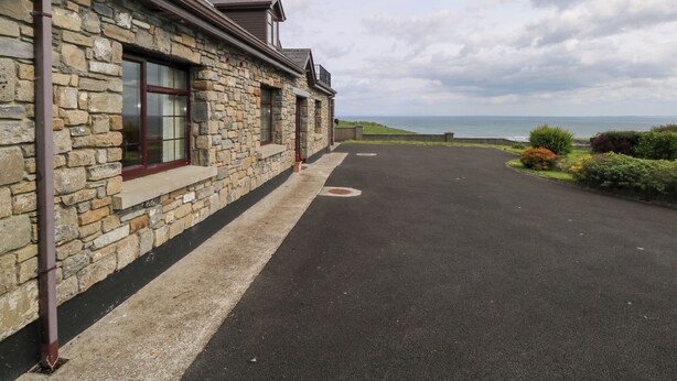 A stone building with a paved driveway and a view of the sea. - Doonalton House (Doonaltan)