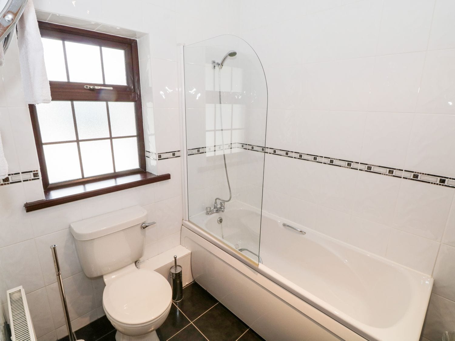 A bathroom with a toilet, a glass-enclosed shower, and a window.