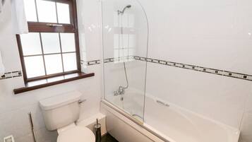 A bathroom with a toilet, a glass-enclosed shower, and a window.