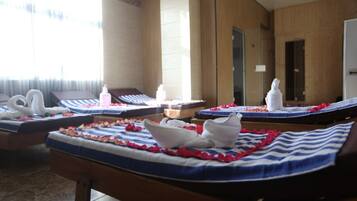 A spa room with multiple massage beds, each adorned with rose petals and white towels.