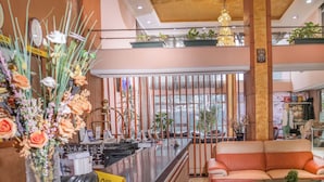 Un hall d’hôtel avec un comptoir d’accueil, un canapé et des plantes décoratives.