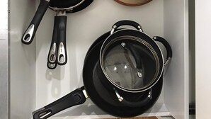 Un tiroir de cuisine contenant divers ustensiles de cuisine, notamment des casseroles, des poêles et une passoire.