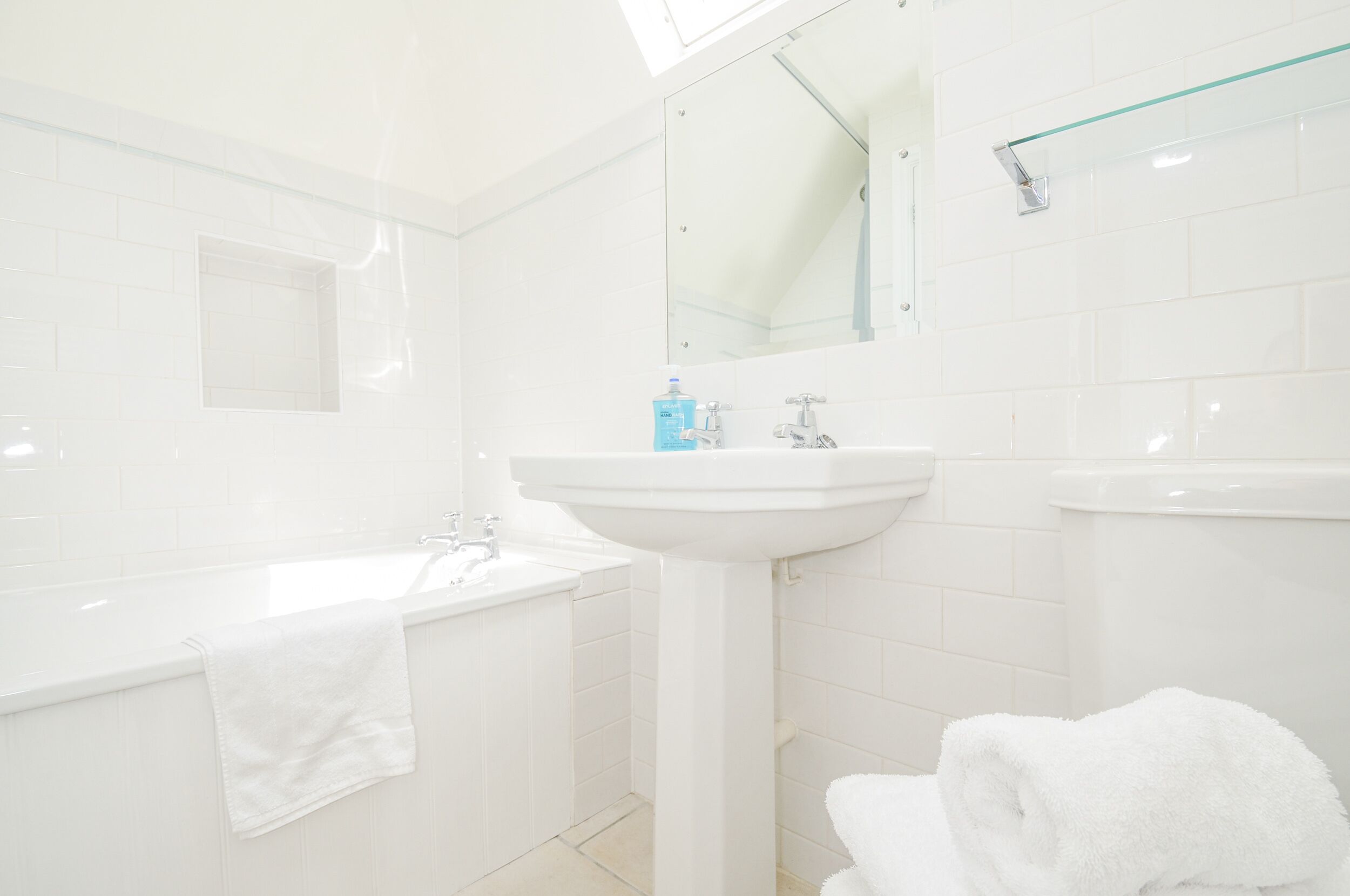 A modern bathroom with a bathtub, a sink, and a mirror.
