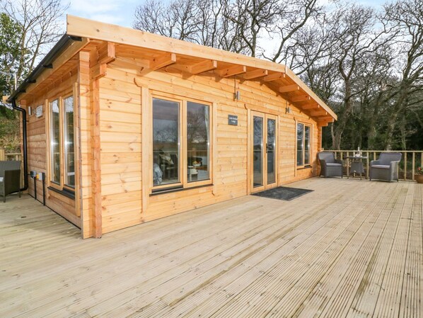 A wooden cabin with large windows, a deck, and a sign indicating it is a "Little Creek Lodge." - Little Orchard Lodge (Truro)