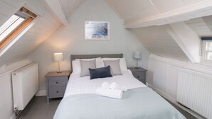 Un dormitorio con una cama, dos mesitas de noche, una lámpara de noche, una ventana y una luz en el techo.