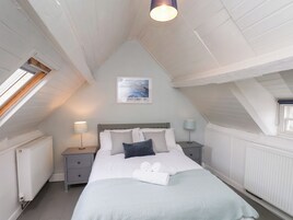 Un dormitorio con una cama, dos mesitas de noche, una lámpara de noche, una ventana y una luz en el techo.