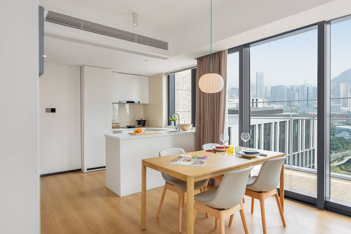 Eine moderne Küche mit weißer Arbeitsplatte und einem Essbereich mit Holztisch und Stühlen.